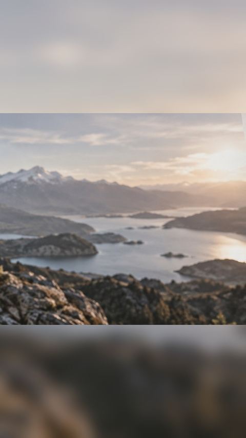 A wide mountain-lake photo expanded to a tall 9:16 story, whole in the middle with blurred sky and rocks above and below.